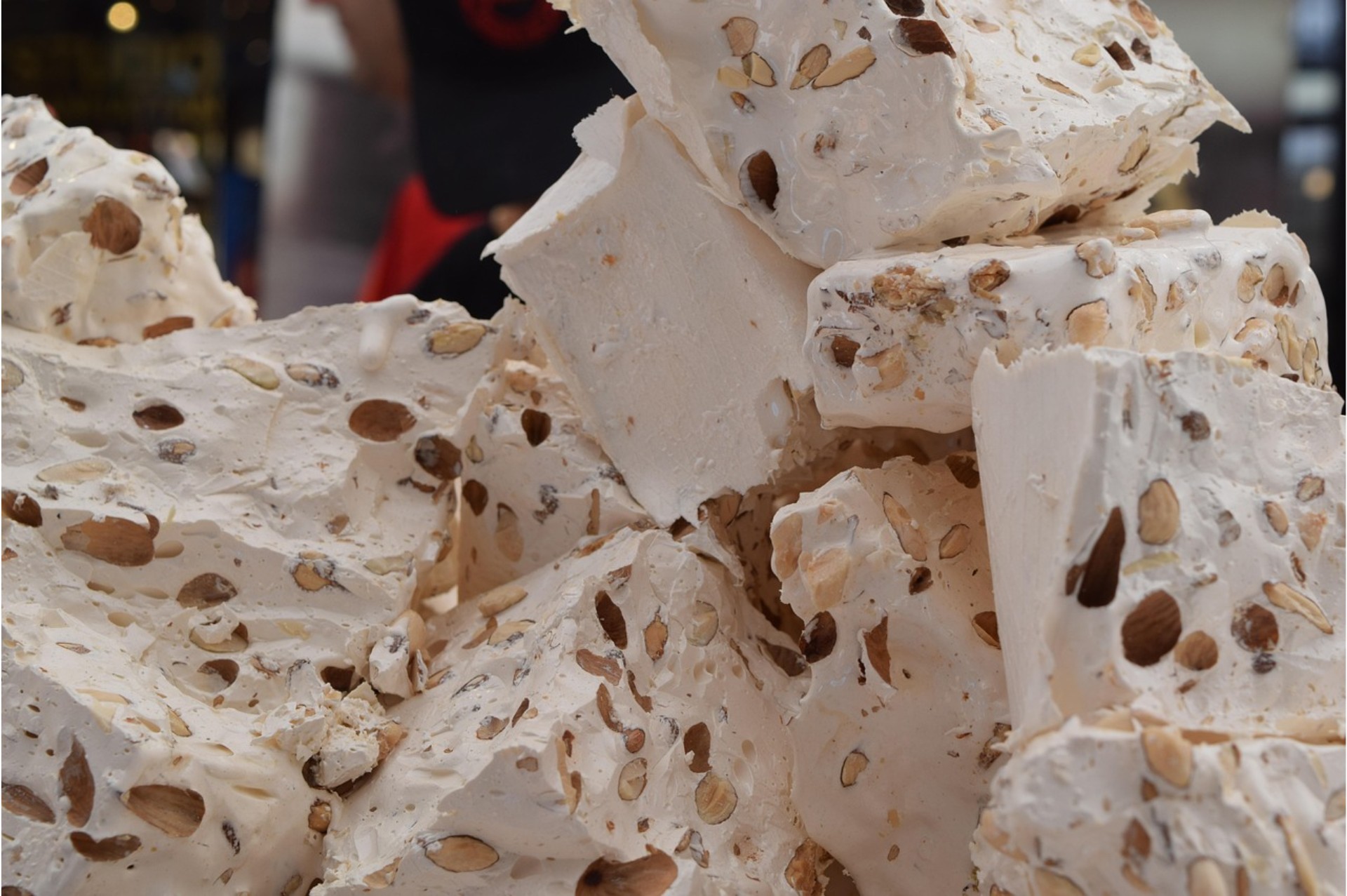 Chunks of Italian torrone nougat with almonds stacked at a Christmas market