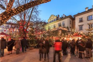 Crowds at Bolzano Christmas Market surrounded by twinkling lights and decorations