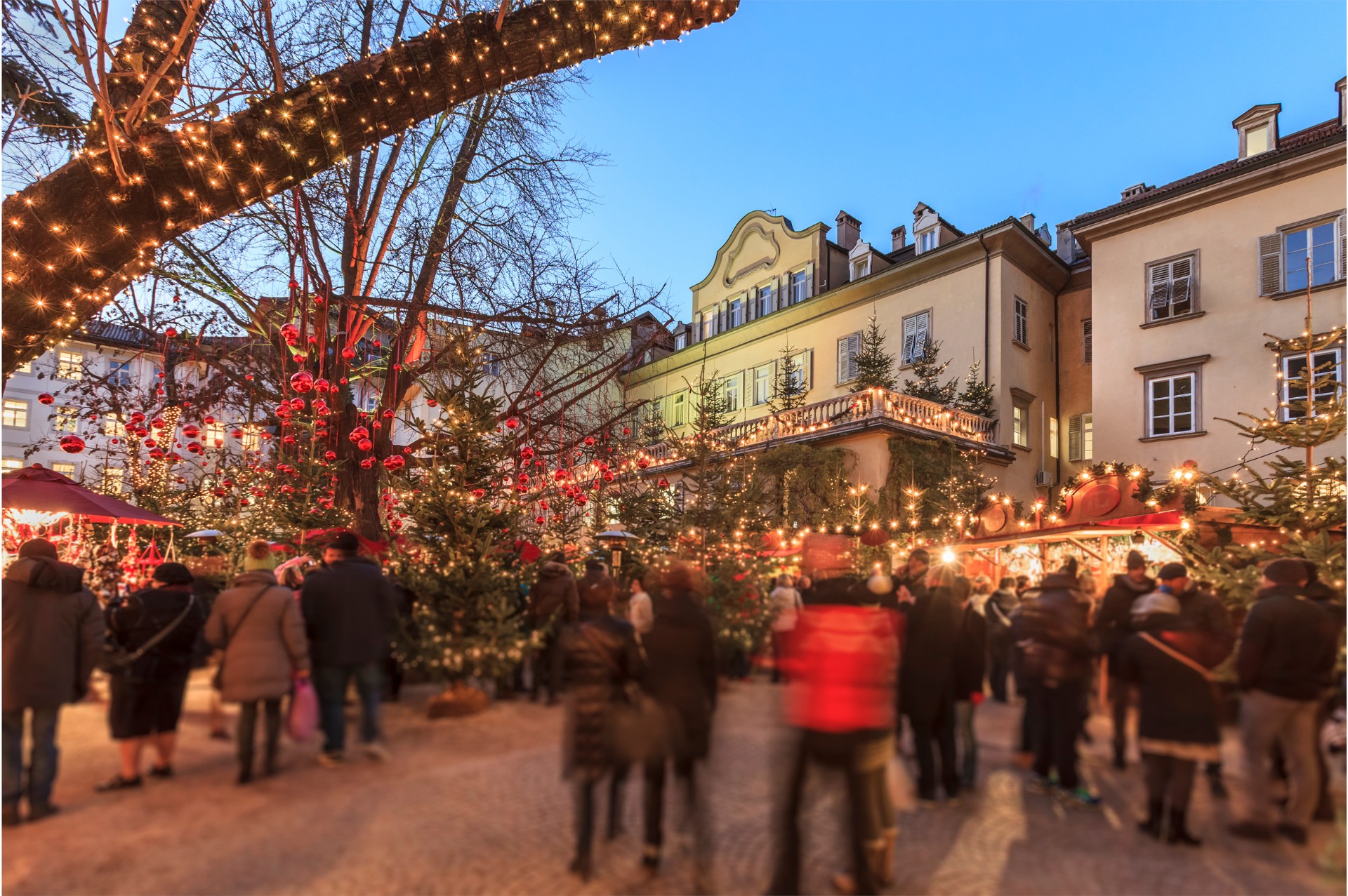 Crowds at Bolzano Christmas Market surrounded by twinkling lights and decorations